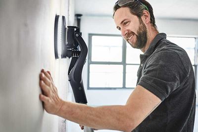 Un hombre utiliza la Planex con luz para lijar una pared